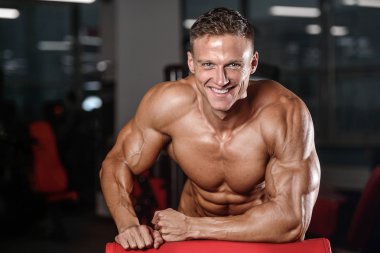 Spor salonunda egzersiz yapan yakışıklı kaslı vücut geliştirmeci erkek