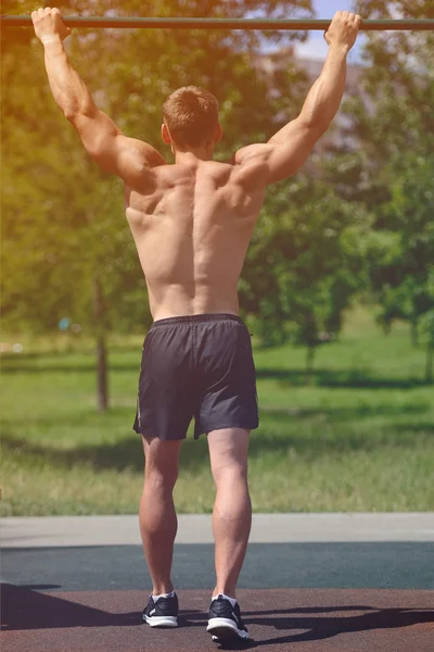 Homem muscular praticar treino de rua em um ginásio ao ar livre — Fotografia de Stock