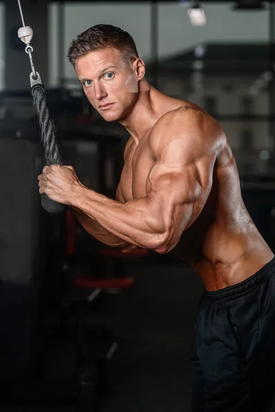 Guapo musculoso culturista hombre haciendo ejercicios en el gimnasio — Foto de Stock