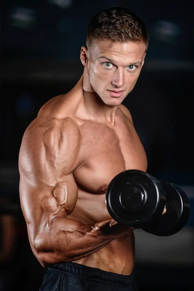 Красивый мускулистый культурист делает упражнения в спортзале — стоковое фото