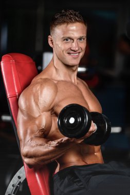 Spor salonunda egzersiz yapan yakışıklı kaslı vücut geliştirmeci erkek