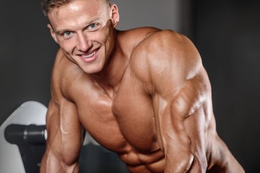 Spor salonunda egzersiz yapan yakışıklı kaslı vücut geliştirmeci erkek