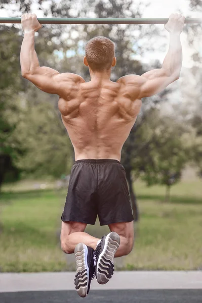 Hombre musculoso practicar entrenamiento callejero en un gimnasio al aire libre — Foto de Stock