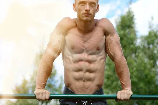 Hombre musculoso practicar entrenamiento callejero en un gimnasio al aire libre — Foto de Stock