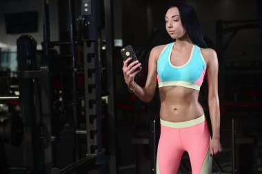 Akıllı telefon tutarak spor salonunda formda kadın