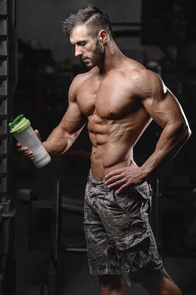 Homme de fitness athlétique beau tenant un shaker et posant gymnase fitness et musculation — Photo
