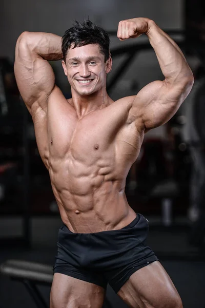 Handsome bodybuilder training in the gym sexy man lift dumbbells — Stock Photo, Image