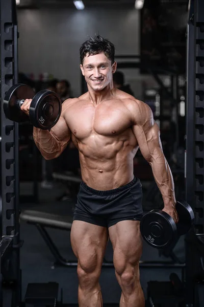 Guapo culturista entrenamiento en el gimnasio sexy hombre levantar pesas —  Fotos de Stock