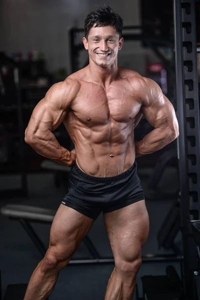 Stilig bodybuilder träning i gym sexig man lyft hantlar — Stockfoto