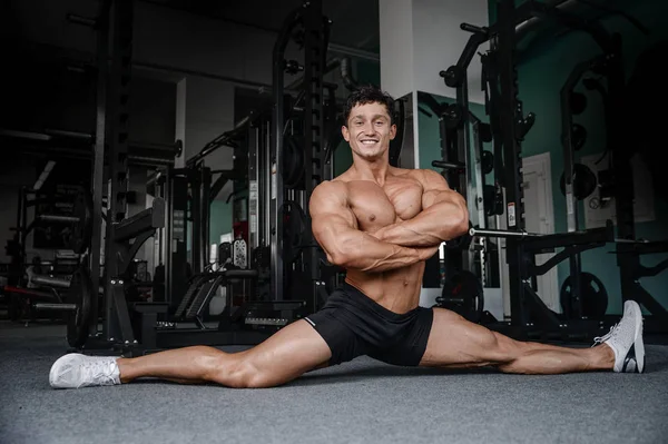Bölmeleri uzanıyor adam spor salonu yakışıklı fitness bacak germe
