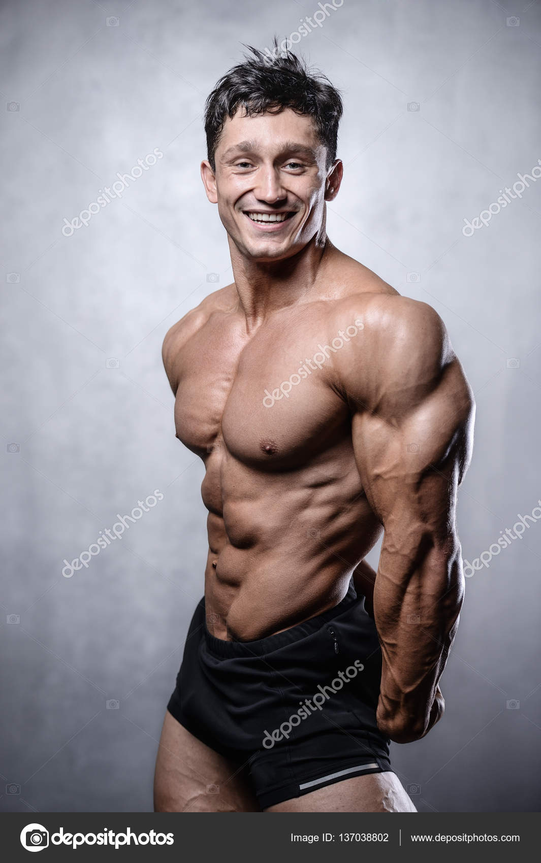 Beautiful fitness male model posing in studio on white grey back Stock