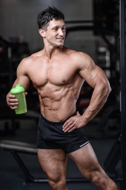 Bir shaker içinde jimnastik salonu kazanç muscl tutan yakışıklı fitness modeli