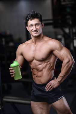 Bir shaker içinde jimnastik salonu kazanç muscl tutan yakışıklı fitness modeli