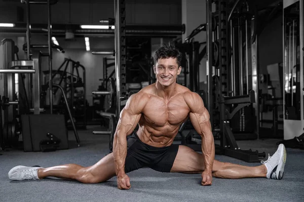 Bölmeleri uzanıyor adam spor salonu yakışıklı fitness bacak germe