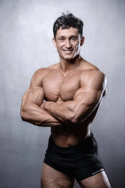 Bela fitness modelo masculino posando em estúdio na parte de trás cinza branco — Fotografia de Stock