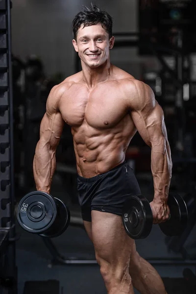 Handsome bodybuilder training in the gym sexy man lift dumbbells — Stock Photo, Image
