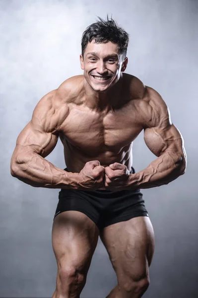 Beautiful fitness male model posing in studio on white grey back — Stock Photo, Image