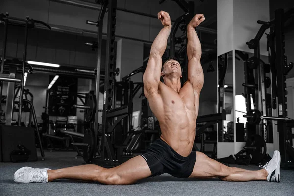 Divide o homem esticando as pernas no ginásio aptidão bonito — Fotografia de Stock