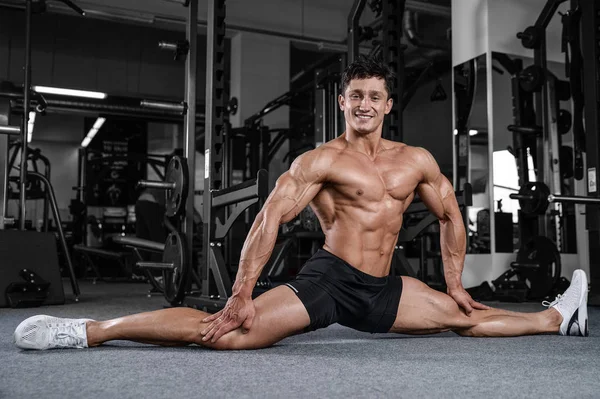 Splits stretches man stretching legs in the gym handsome fitness