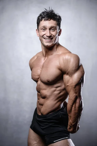 Beautiful fitness male model posing in studio on white grey back — Stock Photo, Image