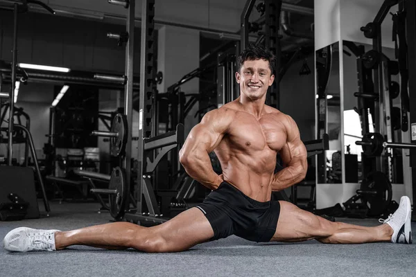 Splits stretches man stretching legs in the gym handsome fitness
