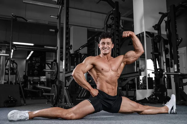 Bölmeleri uzanıyor adam spor salonu yakışıklı fitness bacak germe