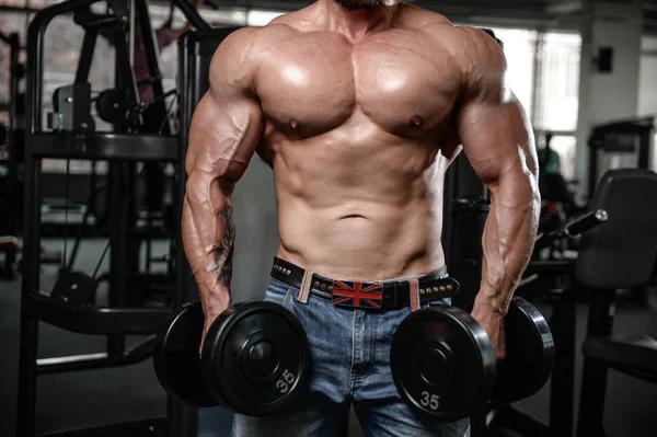 Brutal fuerte culturista hombre bombeando los músculos y entrenar gimnasio — Foto de Stock