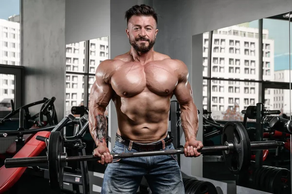 Brutal fuerte culturista hombre bombeando los músculos y entrenar gimnasio — Foto de Stock