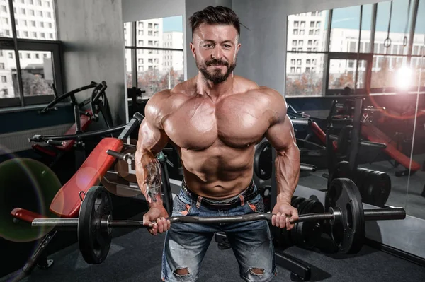 Brutal fuerte culturista hombre bombeando los músculos y entrenar gimnasio — Foto de Stock