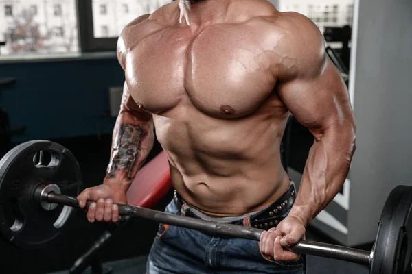 Brutal fuerte culturista hombre bombeando los músculos y entrenar gimnasio — Foto de Stock
