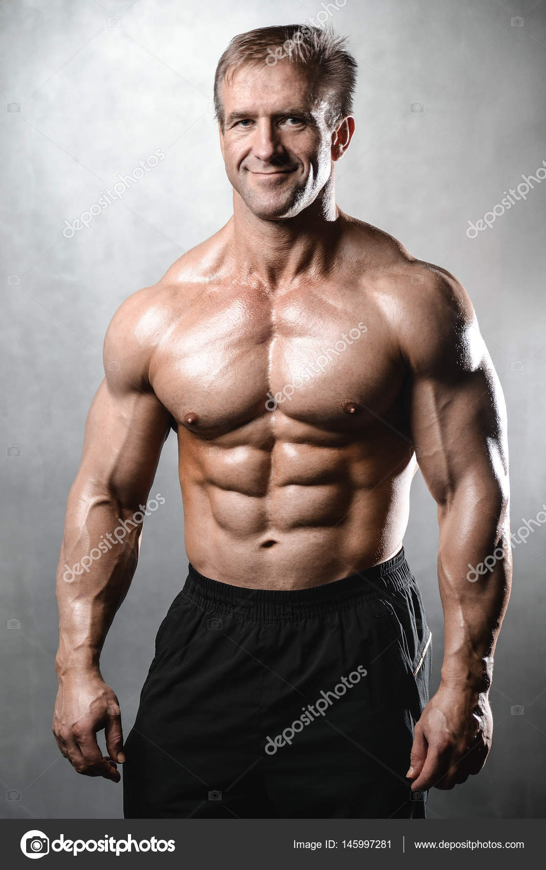 Brutal stark bodybuilder alter mann posiert im studio grey Brutal stark bodybuilder alter mann posiert im studio grey