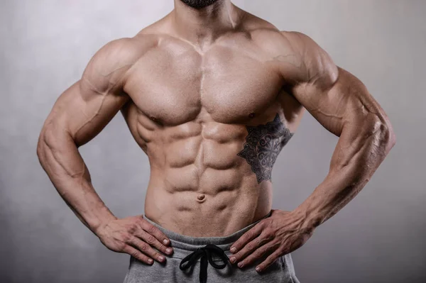 Brutale sterke bodybuilder man poseren in studio op grijze pagina — Stockfoto