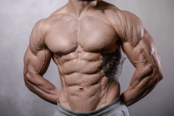 Brutal strong bodybuilder man posing in studio on grey backgroun — Stock Photo, Image