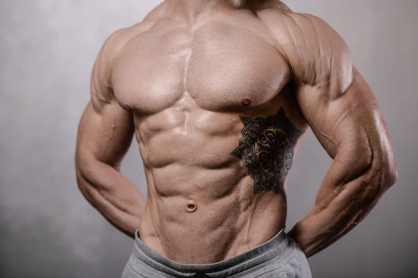 Βάναυση ισχυρή bodybuilder άνθρωπος που θέτουν σε στούντιο στο γκρι backgroun — Φωτογραφία Αρχείου