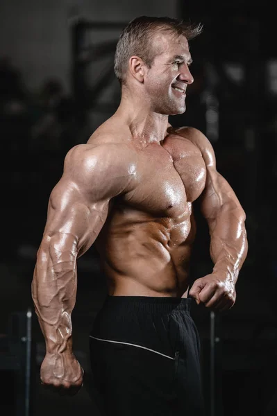 Brutal fuerte culturista hombre bombeando los músculos y entrenar gimnasio — Foto de Stock