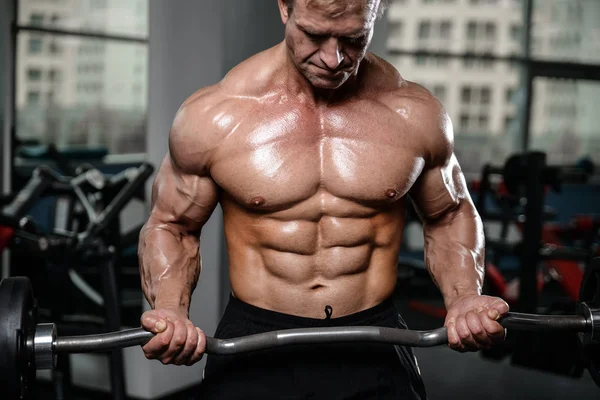 Brutal fuerte culturista hombre bombeando los músculos y entrenar gimnasio —  Fotos de Stock