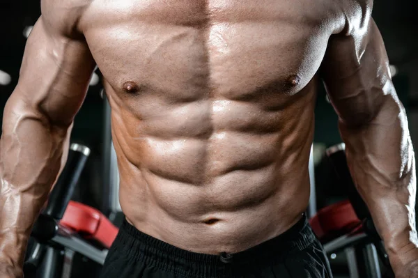 Brutal fuerte culturista hombre bombeando los músculos y entrenar gimnasio — Foto de Stock