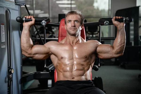 Brutal fuerte culturista hombre bombeando los músculos y entrenar gimnasio — Foto de Stock