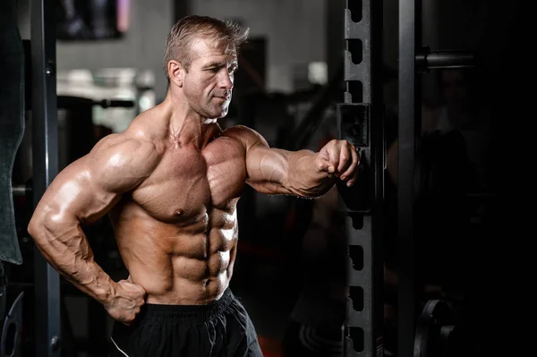 Brutal forte fisiculturista homem bombeando os músculos e treinar ginásio — Fotografia de Stock