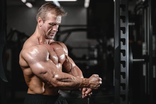 Brutal fuerte culturista hombre bombeando los músculos y entrenar gimnasio — Foto de Stock