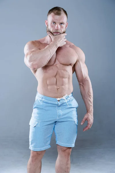 Brutal strong bodybuilder man posing in studio on grey backgroun — Stock Photo, Image