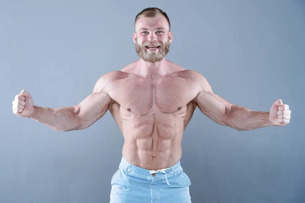 Brutal forte bodybuilder uomo in posa in studio su backgroun grigio — Foto Stock