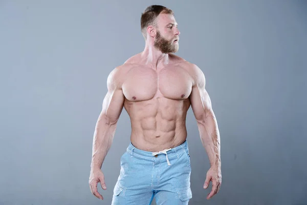 Brutal forte bodybuilder uomo in posa in studio su backgroun grigio — Foto Stock