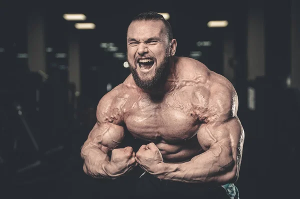 Bonito ajuste caucasiano muscular homem flexionando seus músculos no ginásio — Fotografia de Stock