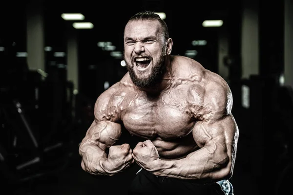 Handsome fit caucasian muscular man flexing his muscles in gym — Stock Photo, Image