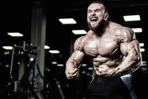 Handsome fit caucasian muscular man flexing his muscles in gym — Stock Photo, Image