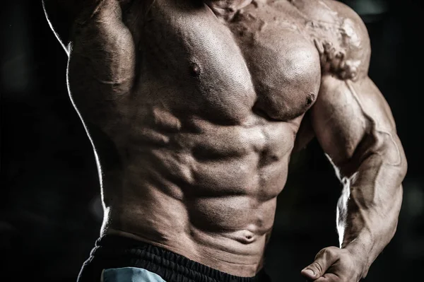 Красивый кавказский мускулистый мужчина, разминающий мышцы в спортзале. — стоковое фото