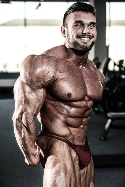 Handsome fit caucasian muscular man flexing his muscles in gym — Stock Photo, Image