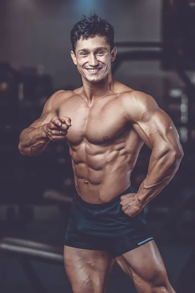 Handsome caucasian muscular man on diet point fingers in gy — Stock Photo, Image
