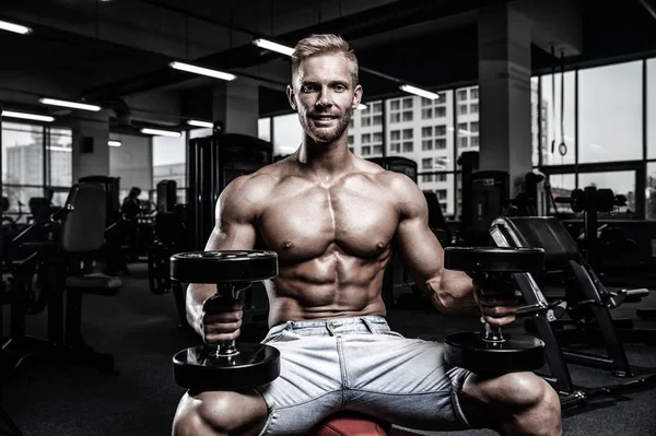 Caucasian sexy fitness male model execute exercise with dumbbell